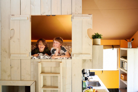 Zwei Kinder genießen einen Baumhausaufenthalt mit Sanitäranlagen im Safari Boomhut auf Camping Goorzicht.