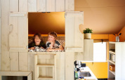 Zwei Kinder genießen einen Baumhausaufenthalt mit Sanitäranlagen im Safari Boomhut auf Camping Goorzicht.