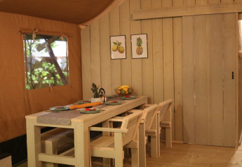 Dining area inside Safaritent Medley with wooden furniture and fruit art on the wall at Camping Goorzicht, Netherlands.