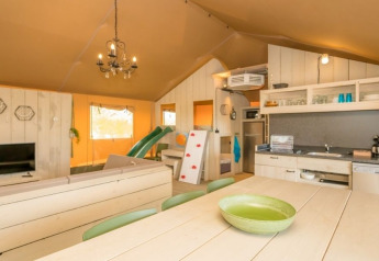 Interno della tenda safari Medley al Camping Goorzicht nei Paesi Bassi con cucina, zona pranzo e salotto.