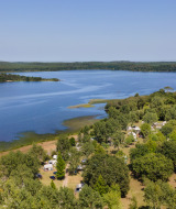 Aerial view of a lake and campsite near Aureilhan, Nouvelle-Aquitaine, France, surrounded by green trees.