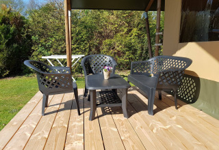 Terrasse eines Safarizeltes mit Kunststoff-Gartenmöbeln und Blumentopf, Recreatiepark de Scherpenhof.
