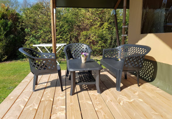 Outdoor terrace at safari tent with plastic garden furniture and flower pot, Recreatiepark de Scherpenhof.