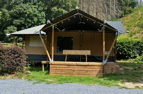 Safari-Zelt mit privatem Sanitärbereich und Holzveranda, eingebettet in grüne Natur und Bäume.