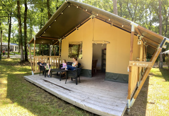 Famiglia che si rilassa sulla veranda di una tenda safari al Vakantiepark Bonte Vlucht nei Paesi Bassi.