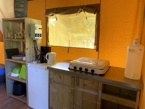 Küchenbereich eines Safarizelts im Vakantiepark Bonte Vlucht, mit Herd, Kühlschrank und Geschirr.