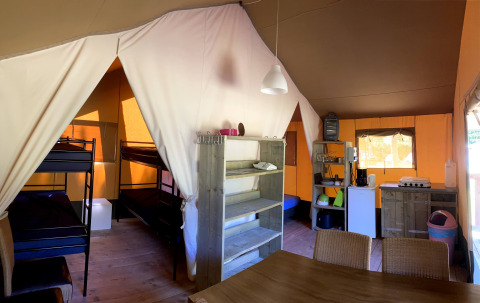 Interior de la tienda Safaritent en Vakantiepark Bonte Vlucht, Países Bajos, con literas y cocina básica.