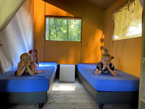 To børn ligger på senge med blå madrasser i en Safaritent i Vakantiepark Bonte Vlucht, Holland.