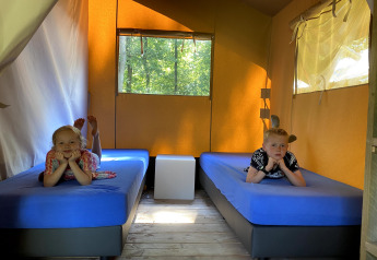 To børn ligger på senge med blå madrasser i en Safaritent i Vakantiepark Bonte Vlucht, Holland.