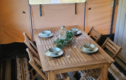 Eettafel met vier houten stoelen in een safaritent bij Camping Reiler in Luxemburg, gedekt voor vier.