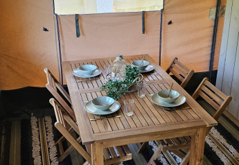 Table à manger en bois avec quatre chaises dans une tente safari au Camping Reiler, Luxembourg.