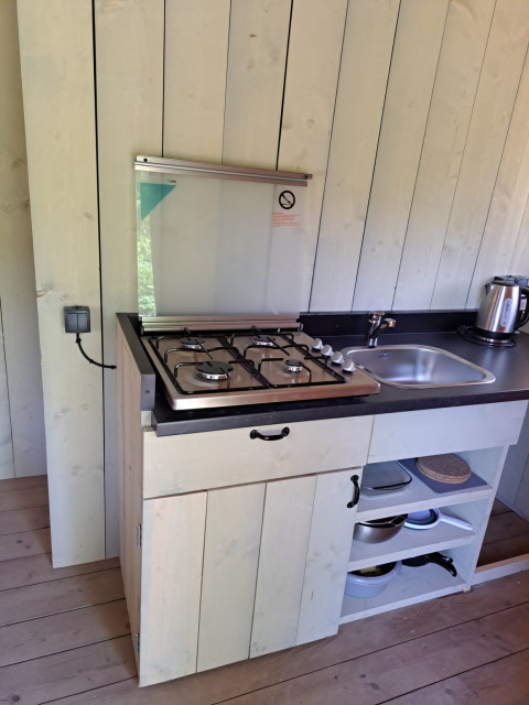 Compacte kitchenette met gasfornuis, gootsteen en waterkoker in safaritent op Camping Reiler, Luxemburg.