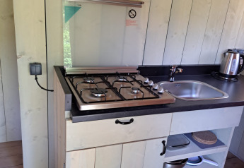 Angolo cottura compatto con fornello a gas, lavello e bollitore in tenda safari al Camping Reiler, Lussemburgo.
