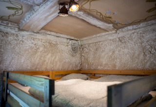 Højseng i Hobbit-hytte ved Familiepark Goolderheide i Belgien med hyggelig indretning og dekoreret loft.
