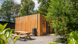 Vue extérieure du lodge Chalet avec murs en bois, table de pique-nique et verdure environnante.