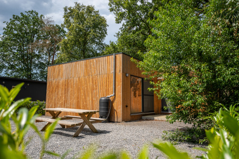Vista esterna del lodge Chalet con rivestimento in legno, tavolo da picnic e vegetazione rigogliosa.