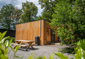 Outdoor view of the Chalet lodge with wooden panel walls, picnic table, and lush greenery around.