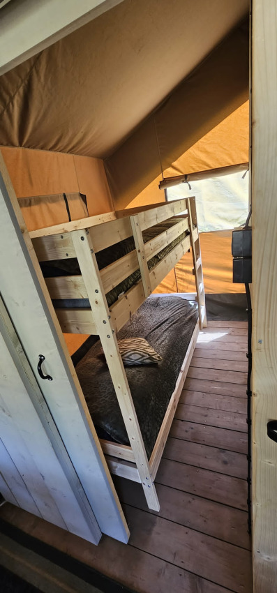 Binnenkant van een safaritent met houten stapelbed en houten vloer bij Camping Reiler in Luxemburg.