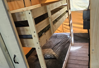 Intérieur d'une tente safari avec lits superposés en bois et plancher au Camping Reiler au Luxembourg.
