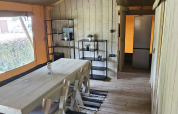 Safari-Zelt mit Holzboden, Esstisch, Stühlen und Regal bei Camping Reiler in Luxemburg.