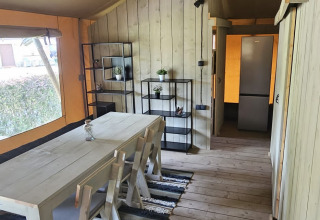 Safari-Zelt mit Holzboden, Esstisch, Stühlen und Regal bei Camping Reiler in Luxemburg.