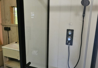 Cabine de douche moderne avec portes en verre et douche à effet pluie dans une tente safari au Camping Reiler, Luxembourg.