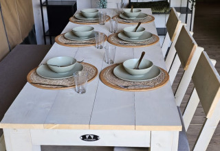 Eettafel met servies in een safaritent bij Camping Reiler, Luxemburg, met houten wand en moderne rekken.