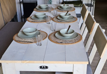 Eettafel met servies en decoratie in een safaritent op Camping Reiler, Luxemburg, met houten wand en rekjes.