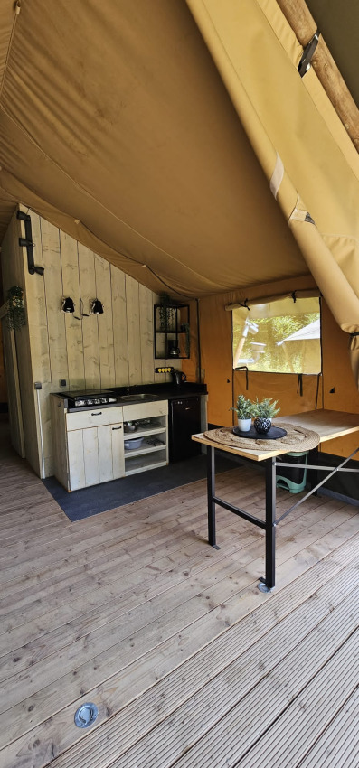 Vue intérieure d'une tente safari avec cuisine et table à manger au Camping Reiler au Luxembourg.