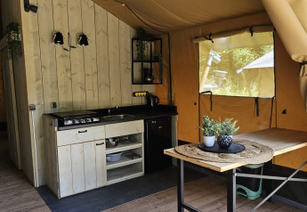 Interieur van een safaritent met keuken en tafel op Camping Reiler in Luxemburg.