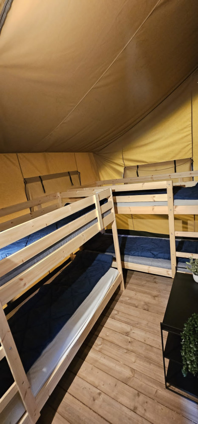 Interior of a safari tent with wooden bunk beds and flooring at Camping Reiler in Luxembourg.