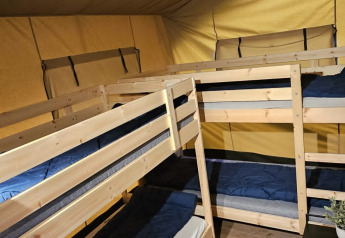Binnenkant van een safaritent met houten stapelbedden en vloer op Camping Reiler in Luxemburg.