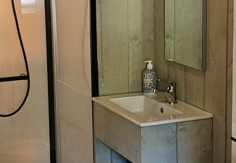 Salle de bain avec douche, lavabo, miroir et toilettes dans une tente safari au Camping Reiler au Luxembourg.