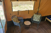 Interno di una tenda safari con due sedie, tavolino e tappeto su pavimento in legno a Camping Reiler, Lussemburgo.