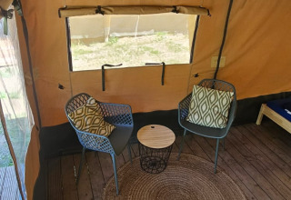 Intérieur d'une tente safari avec deux chaises, table d'appoint et tapis sur plancher au Camping Reiler, Luxembourg.