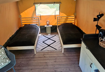 Binnenkant van een safaritent op Camping Reiler in Luxemburg met twee bedden, tapijten en houten vloer.