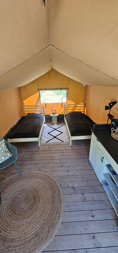 Intérieur d'une tente safari au Camping Reiler au Luxembourg, avec deux lits simples et un plancher en bois.