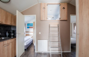 Interior of a lodge with kitchen, bedrooms, and loft ladder at Vakantiepark Leukermeer in the Netherlands.