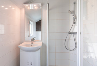 Moderne badkamer met wastafel en douche in de Lodge bij Vakantiepark Leukermeer, Nederland, witte tegels.