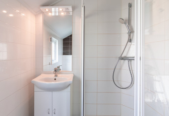 Baño moderno con lavabo y ducha de la Lodge en Vakantiepark Leukermeer, Países Bajos, paredes blancas.