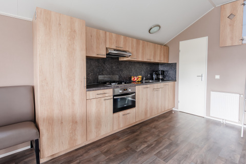 Moderne kitchenette in lodge bij Vakantiepark Leukermeer, Nederland, met houten kasten en inbouwapparatuur.