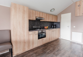 Moderne tekøkken i Lodge på Vakantiepark Leukermeer, Holland med træskabe og integrerede apparater.