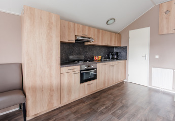 Cocina moderna en lodge de Vakantiepark Leukermeer, Países Bajos, con armarios de madera y electrodomésticos empotrados.