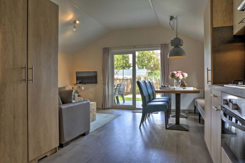 Modern lodge-interieur op Vakantiepark Leukermeer in Nederland met eethoek en toegang tot de tuin.