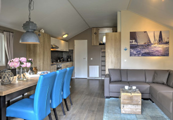 Moderne Lodge mit blauen Stühlen, Ecksofa und Segelbild im Vakantiepark Leukermeer in den Niederlanden.