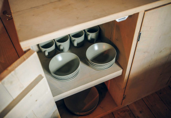 Open kast in een safaritent bij Wilsumer Berge, Duitsland, met borden en kopjes binnenin.