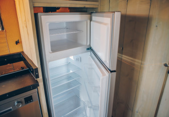 Ein leerer Kühlschrank mit offenem Gefrierfach in einem Safarizelt im Wilsumer Berge, Deutschland.