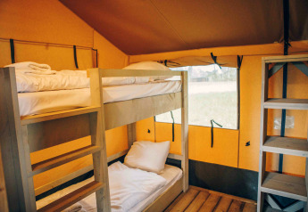 Interieur van een safaritent op Wilsumer Berge in Duitsland met stapelbedden en houten vloer.