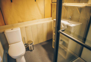 Badezimmer im Safarizelt bei Wilsumer Berge, Deutschland, mit WC, Waschbecken und Holzdetails.
