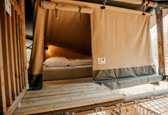 Ingang van safaritent met houten terras en bed, Wilsumer Berge, Duitsland, comfortabele accommodatie.